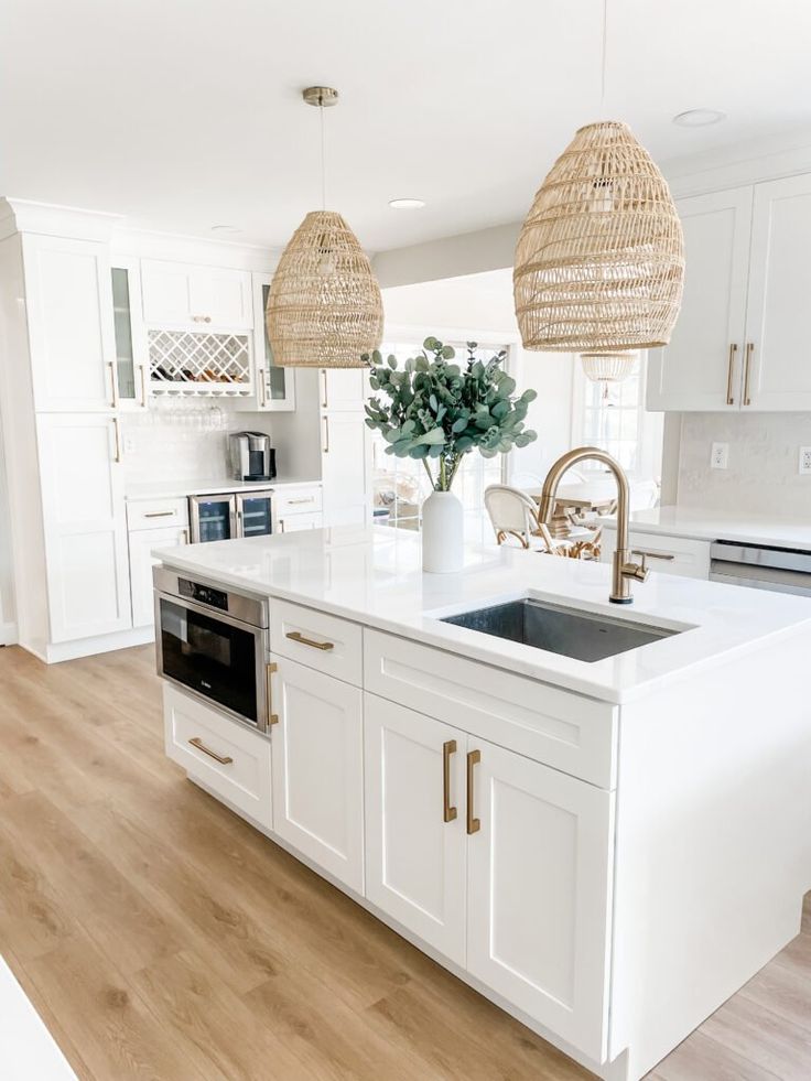 a kitchen with white cabinets and wooden floors, two hanging baskets over the sink area