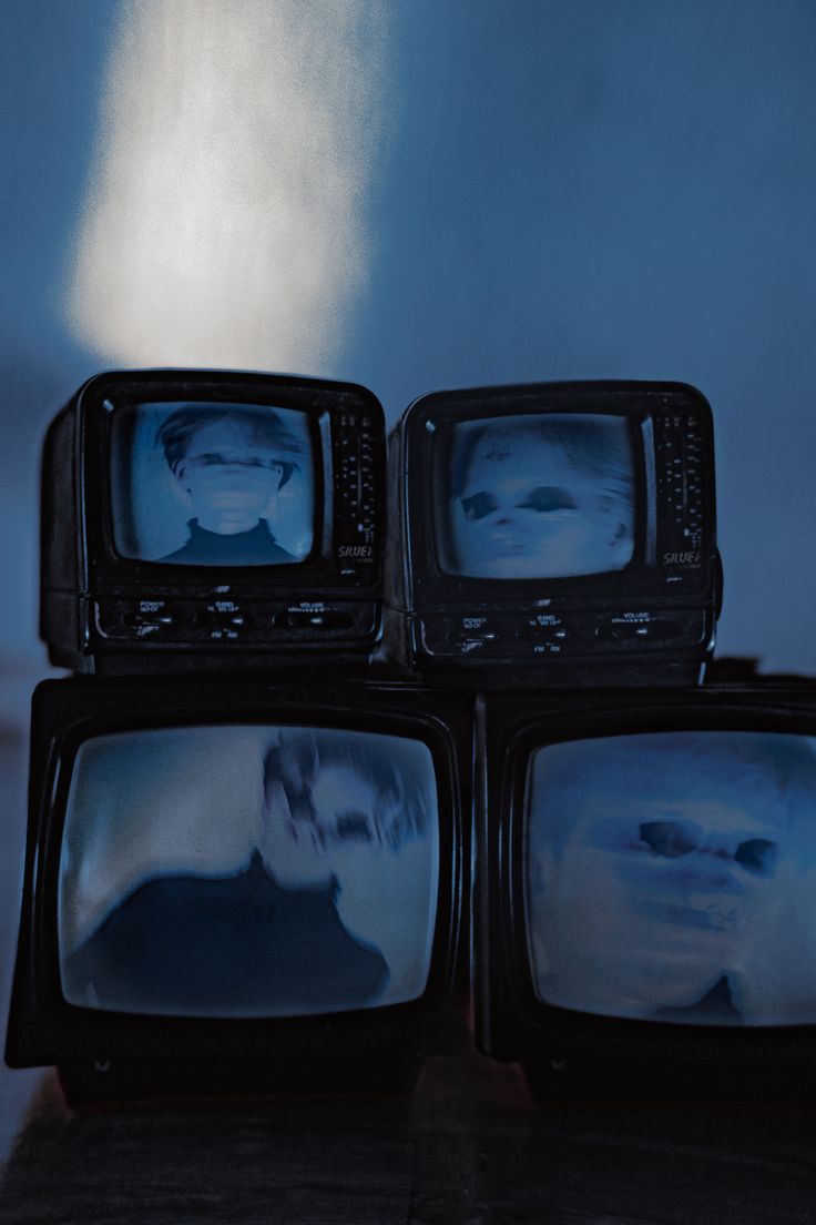 three televisions with faces on them sitting next to each other in front of a blue background