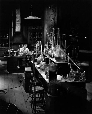 black and white photograph of lab equipment in an old fashioned laboratory room with stools