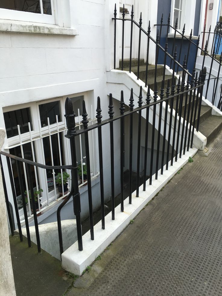 a black iron fence next to a white building