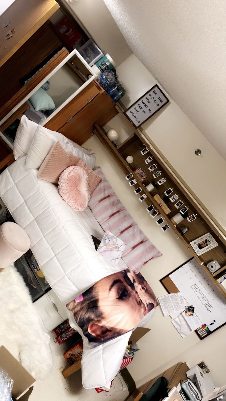 a bedroom with a bed, desk and pictures hanging on the wall in front of it