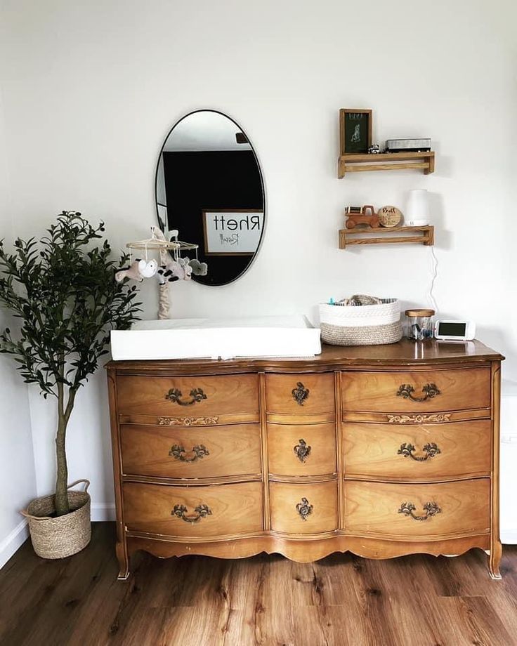 a wooden dresser sitting on top of a hard wood floor next to a potted plant