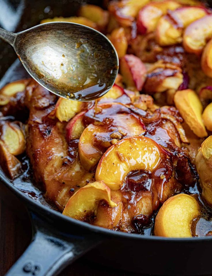 a pan filled with meat covered in apples and sauce being drizzled over it