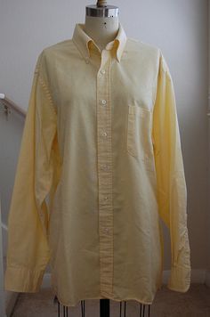 a yellow shirt sitting on top of a mannequin's head in front of a white wall