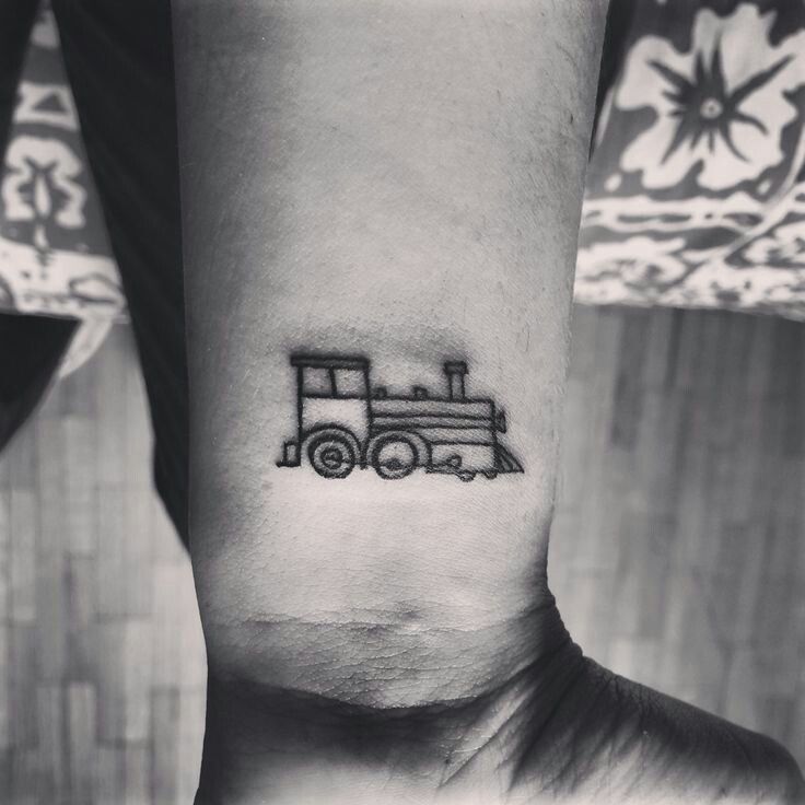 a black and white photo of a small train tattoo on the left inner arm,