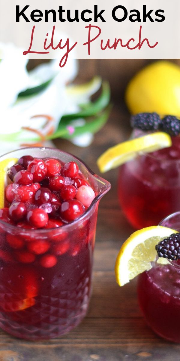 a pitcher filled with liquid and garnished with berries next to sliced lemons