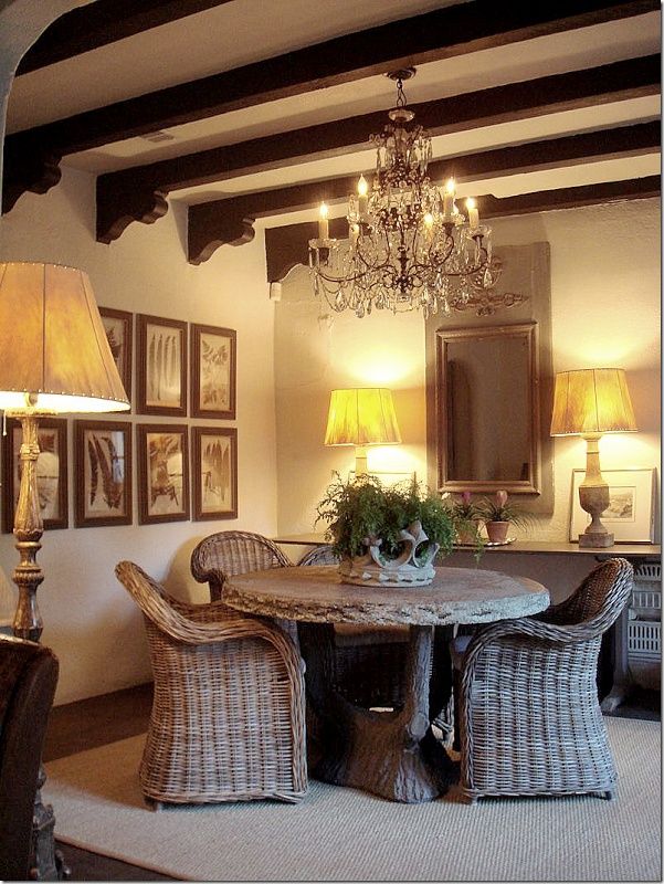 a dining room table with wicker chairs and a chandelier hanging from the ceiling