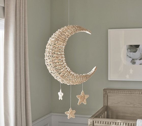 a baby crib with a moon and stars hanging from it