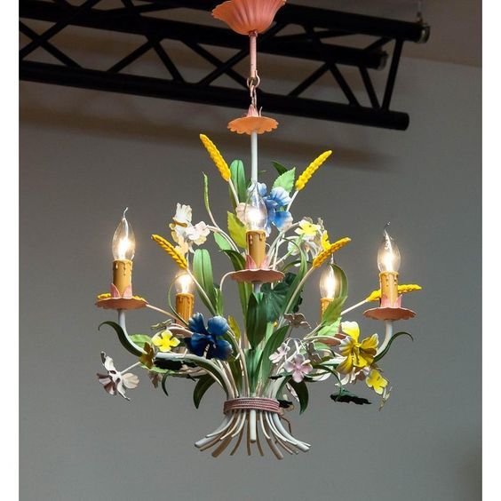 a chandelier with flowers and candles hanging from it