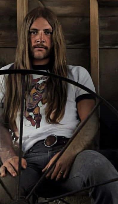 a man with long hair sitting in a chair