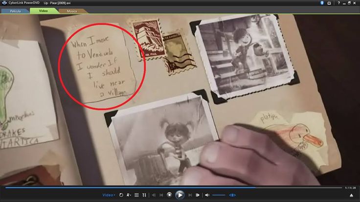 a person holding a piece of paper with pictures and letters on it, in front of an open book