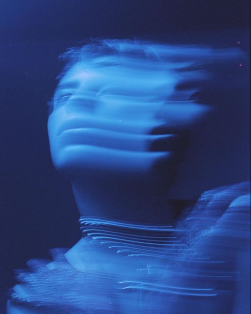 a blurry photo of a woman's face with blue light in the background