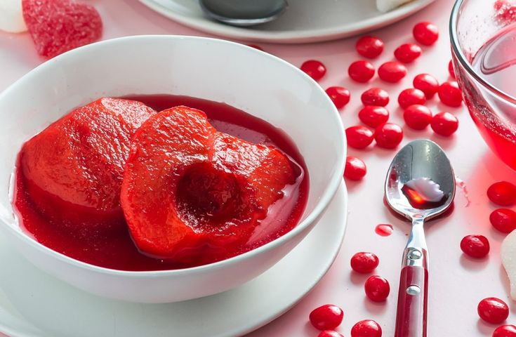 two white bowls filled with red liquid next to silver spoons