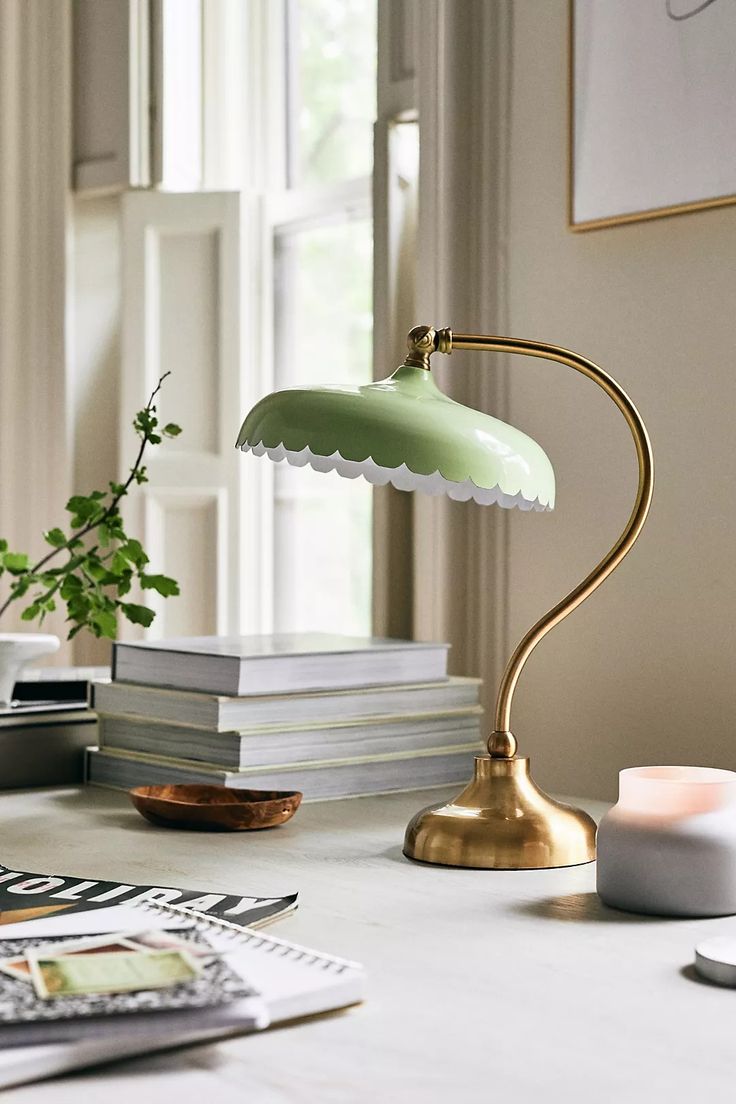 a green lamp sitting on top of a table next to a stack of books and a potted plant