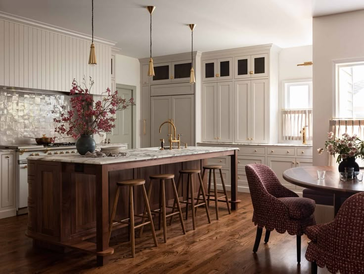 a large kitchen with wooden floors and white cabinetry, along with bar stools