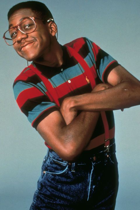 a man with glasses and a striped shirt is posing for a photo in front of a blue background