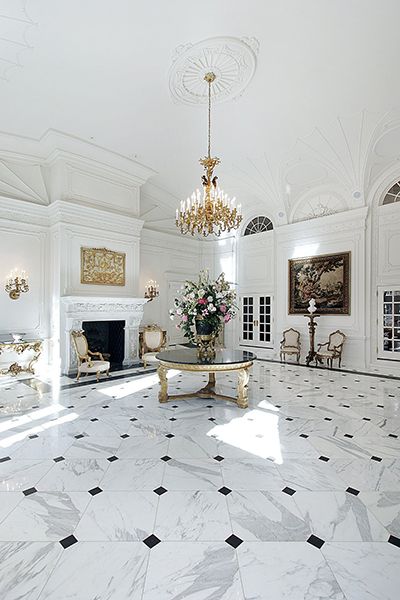 an elegant living room with marble floors and chandelier hanging from the ceiling, surrounded by white walls