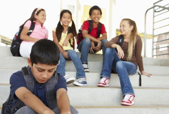 a group of young children sitting on the steps together, one boy is pointing at something in his hand