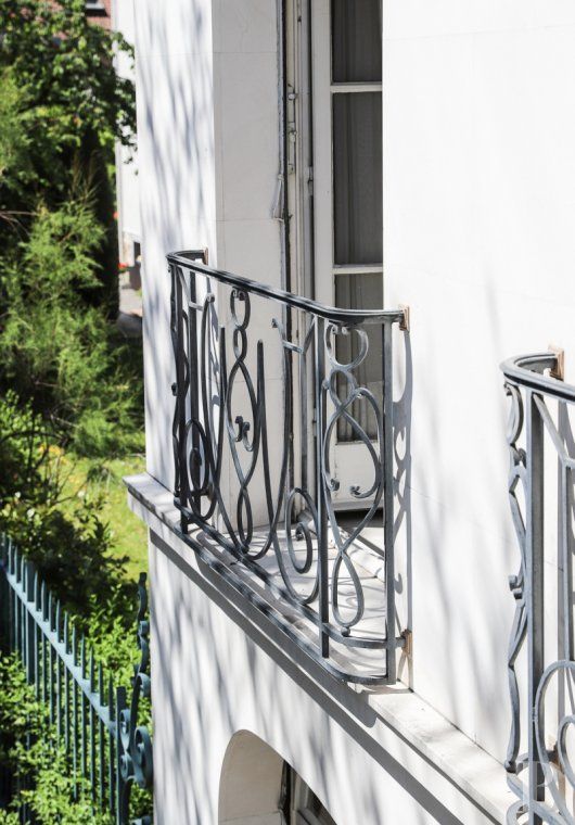 a balcony with wrought iron railings and white walls