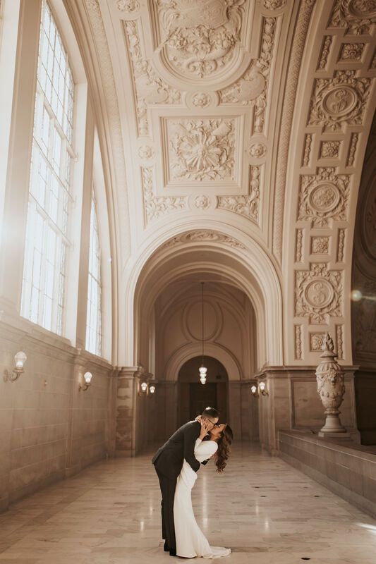 a bride and groom kissing in an ornate building