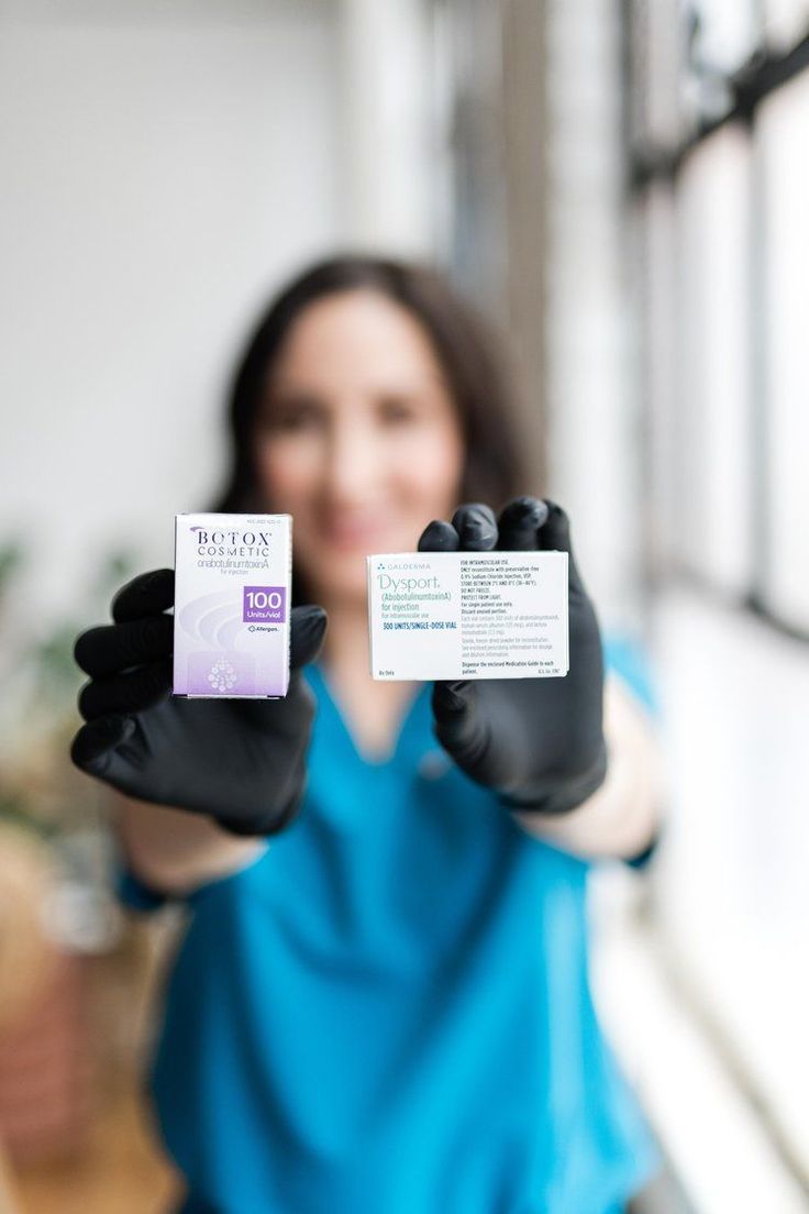 a woman holding up two packets of medicine