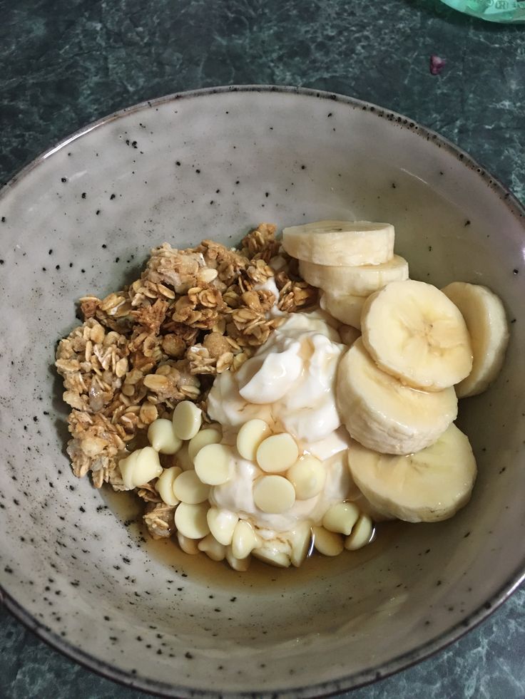 a bowl filled with granola, bananas and yogurt on top of a table