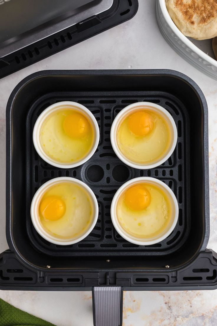 four eggs in an air fryer on top of a counter next to other food items