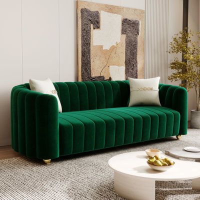 a living room with a green velvet couch and coffee table