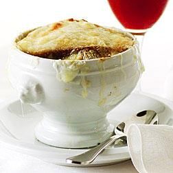 a white bowl filled with food on top of a plate next to a glass of wine