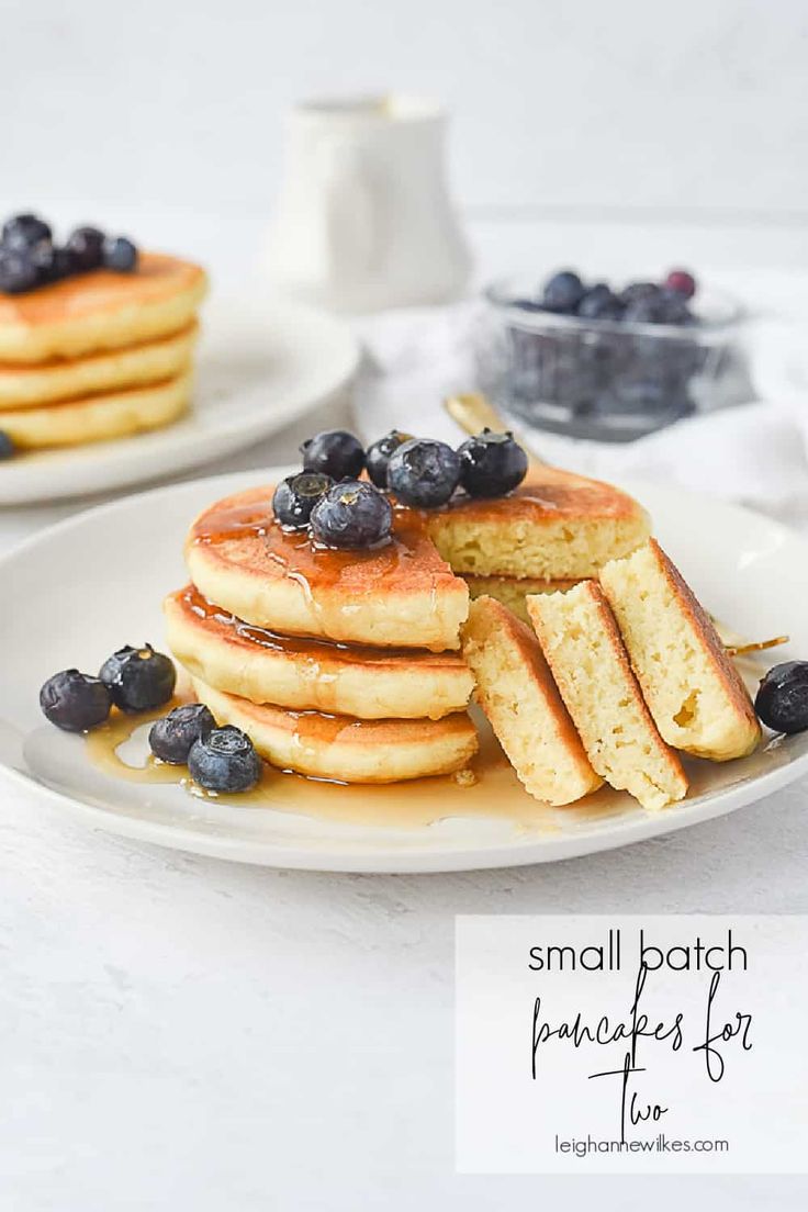 stack of pancakes with blueberries and syrup on white plate