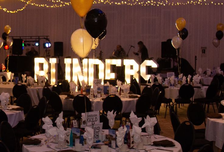 tables and chairs are set up for an event with balloons, streamers and lights