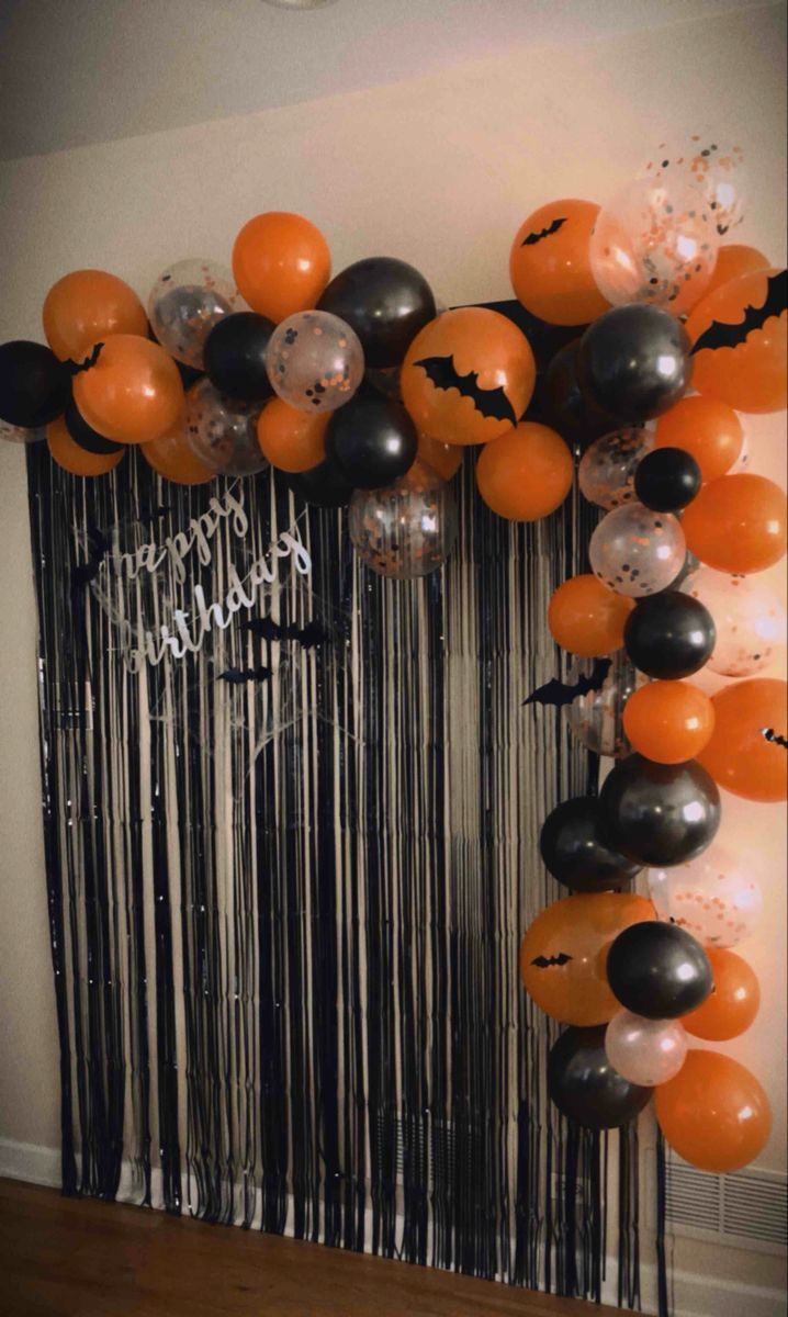 an orange and black balloon arch with halloween decorations