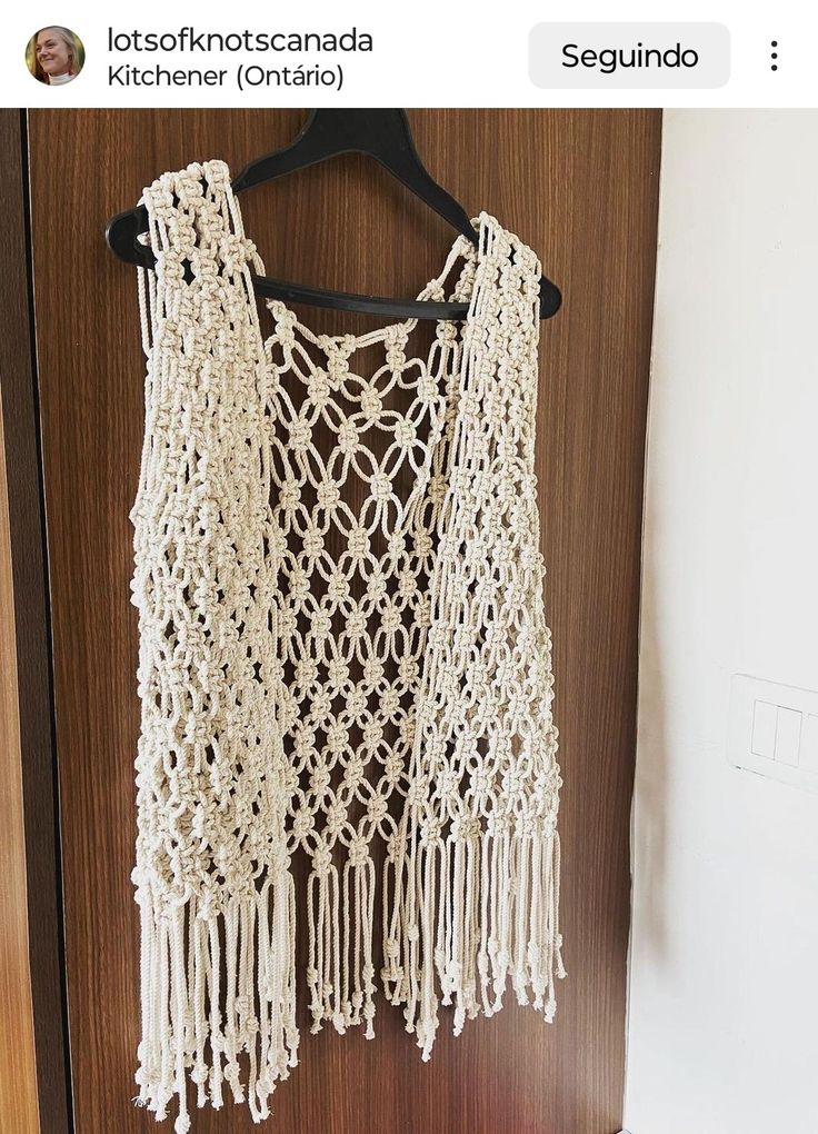 a white crocheted top hanging on a wooden door