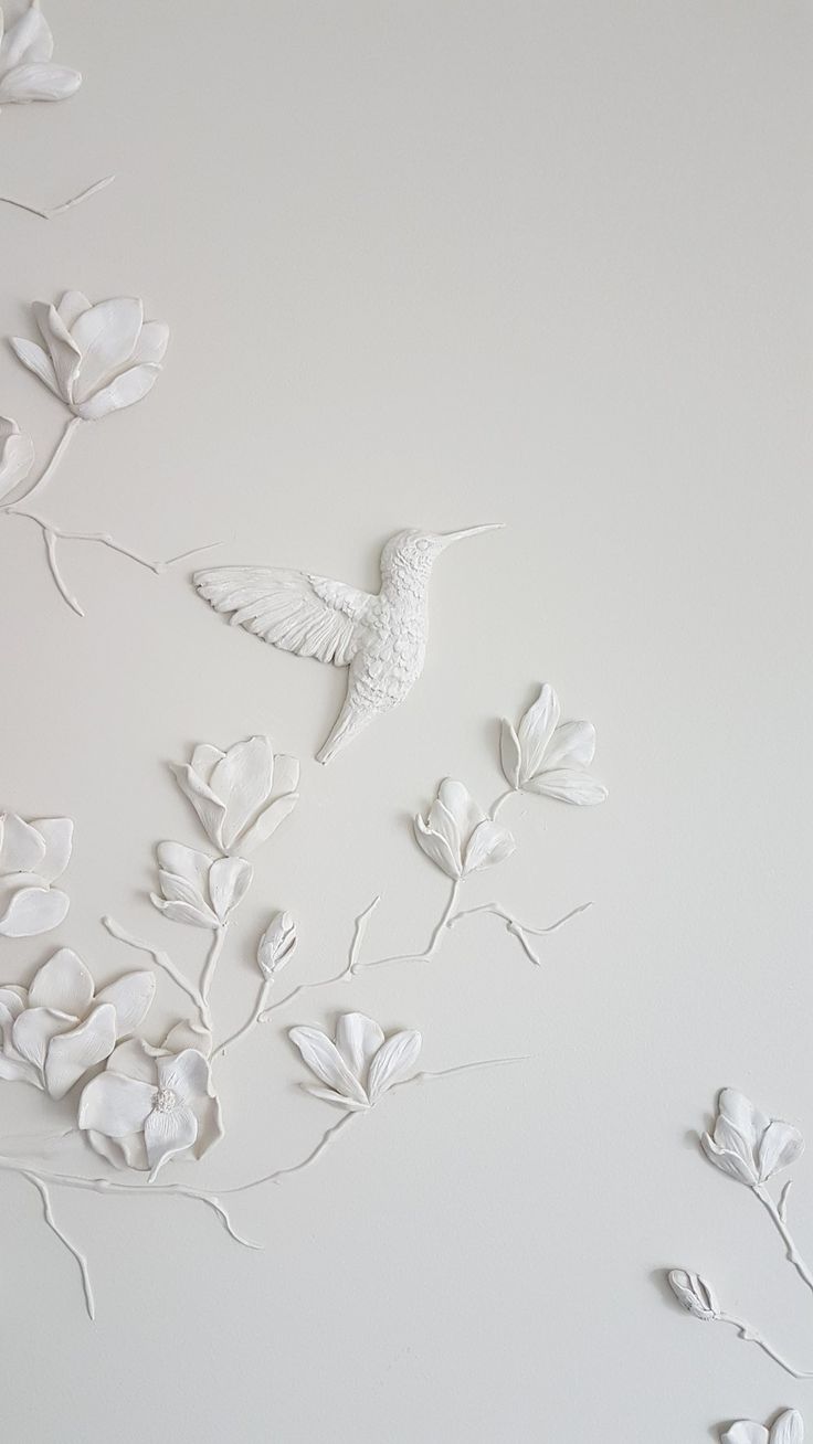 the wall is decorated with white flowers and a bird on it's back side