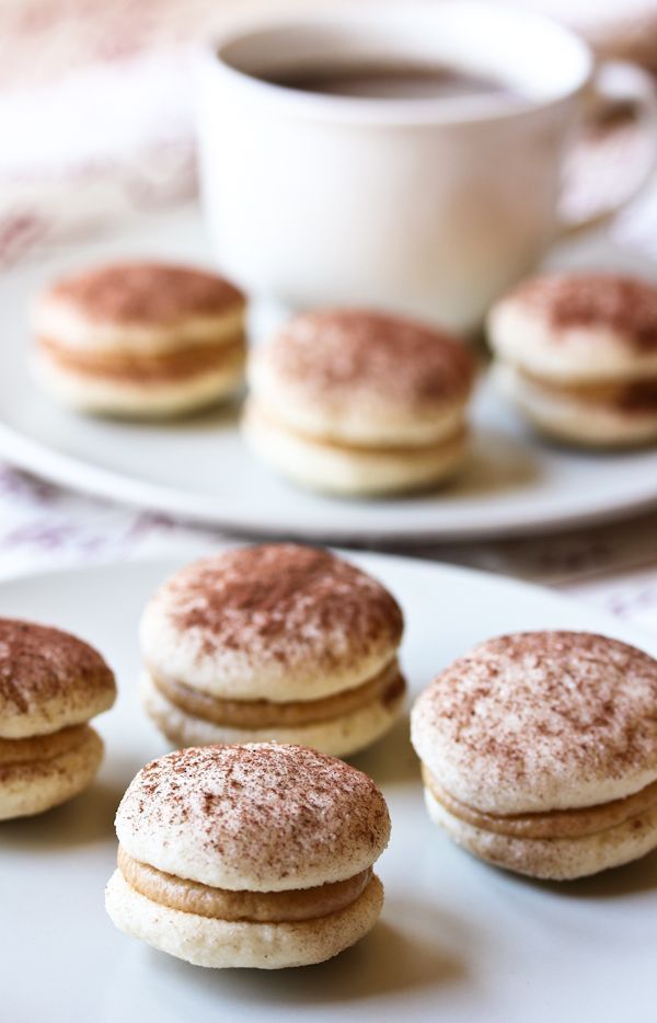 some powdered donuts are on a plate next to a cup of coffee