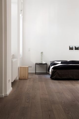 a bedroom with white walls and wood floors