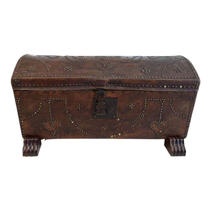 an old leather trunk with metal studding on the top and bottom, sitting on wooden legs