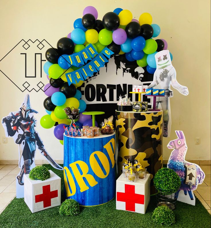 a birthday party with balloons and decorations on the grass in front of a sign that says fortnite