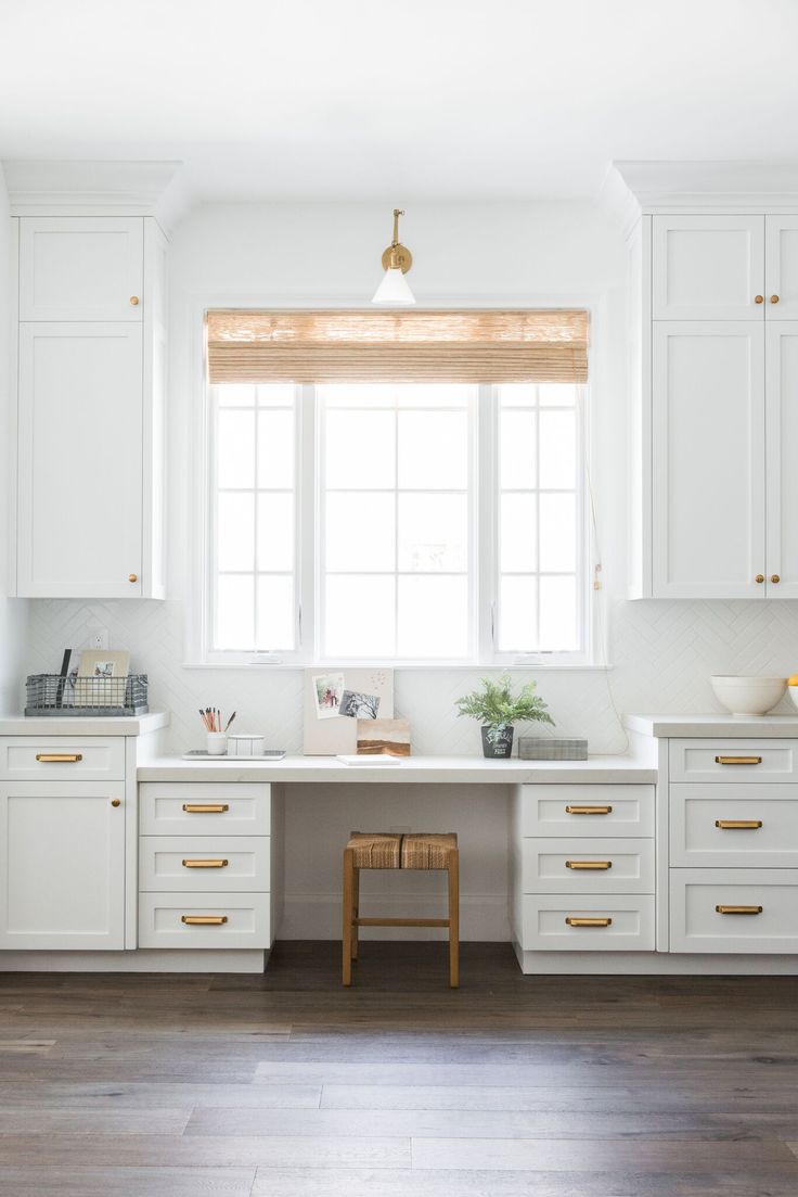 a kitchen with white cabinets and gold hardware on the countertop, along with a stool