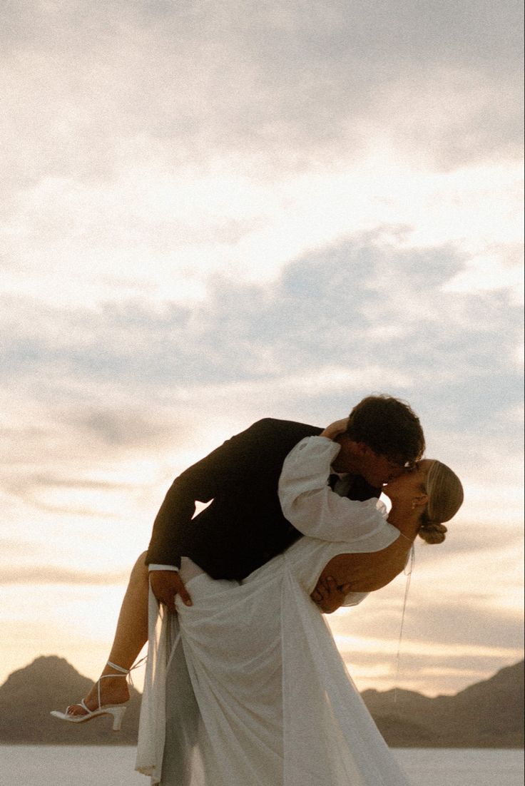 a bride and groom kissing in the desert