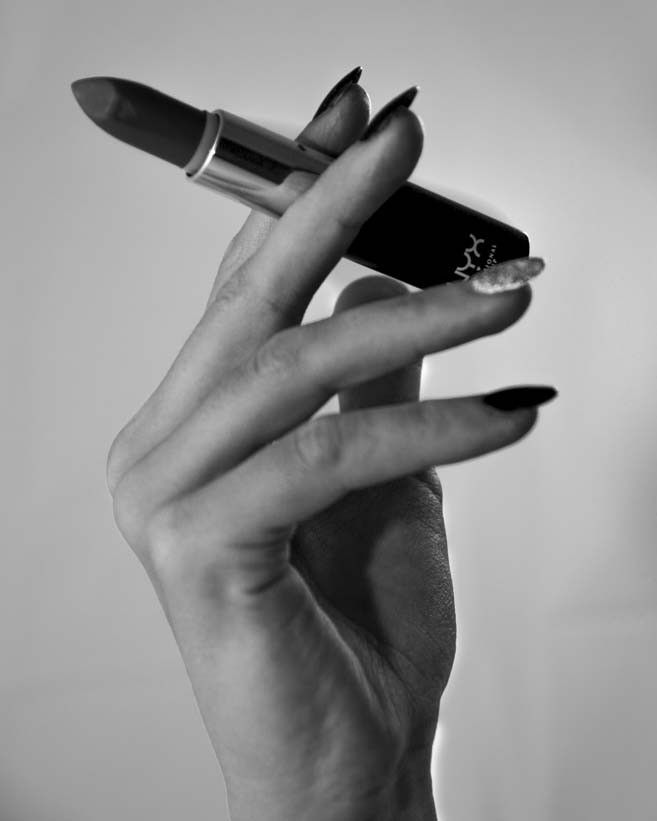 a woman's hand holding a lipstick in black and white