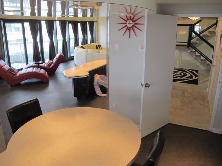 an office with white walls and black leather chairs around a round dining table in the center