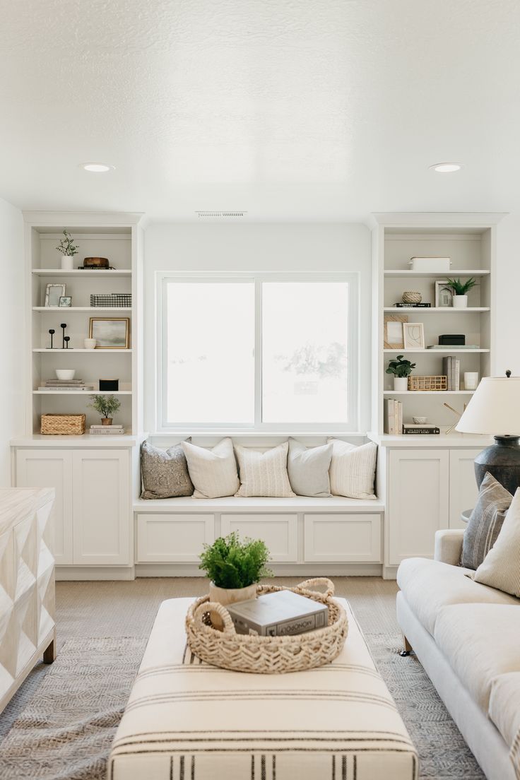 a living room filled with white furniture and lots of bookshelves on the wall