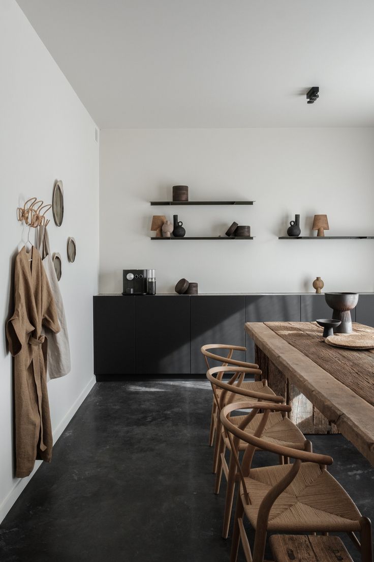 a long wooden table sitting in the middle of a room next to a wall with shelves on it