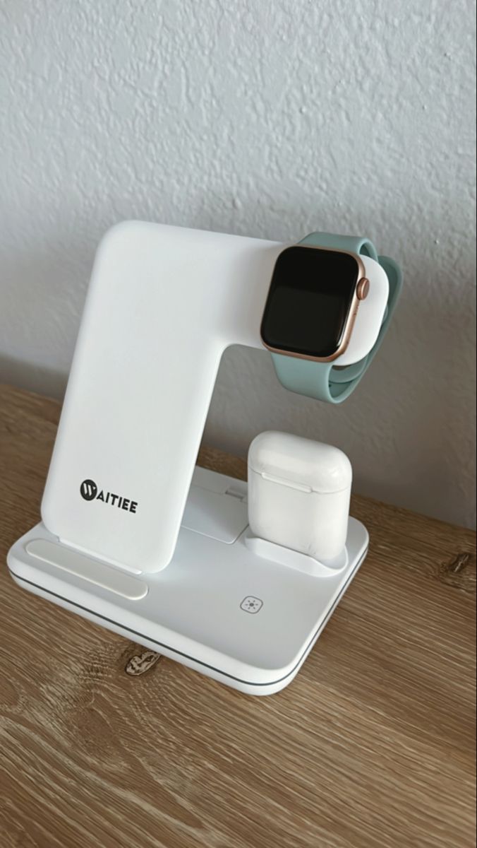 an apple watch and airpods charging station on top of a wooden table next to a white wall