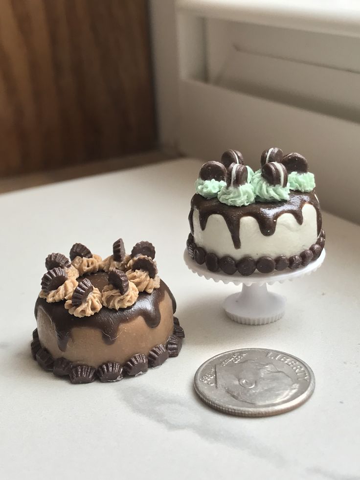 two cakes sitting on top of a white table next to a quarter penny and window sill