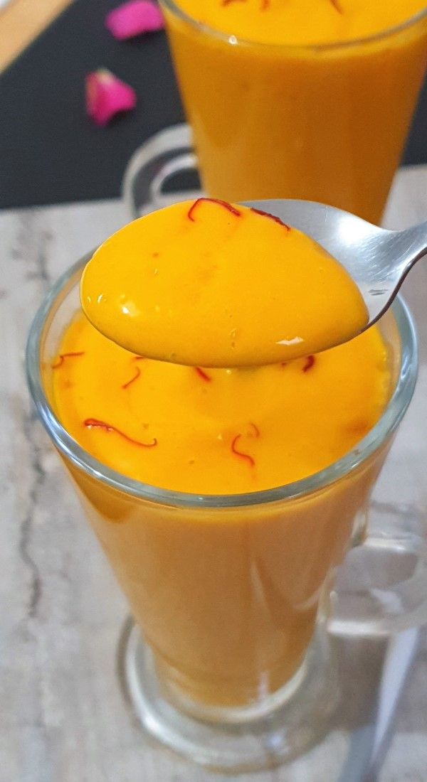 two glasses filled with orange liquid on top of a table