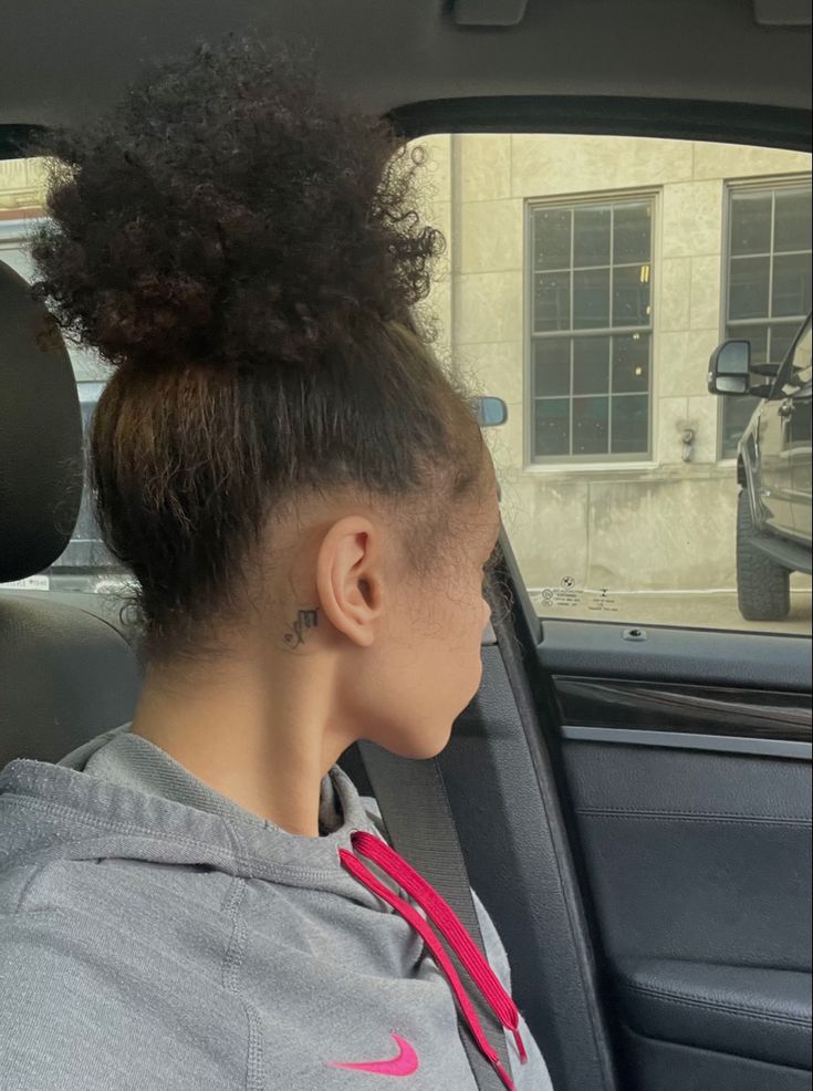 a young woman sitting in the back seat of a car with her hair tied up