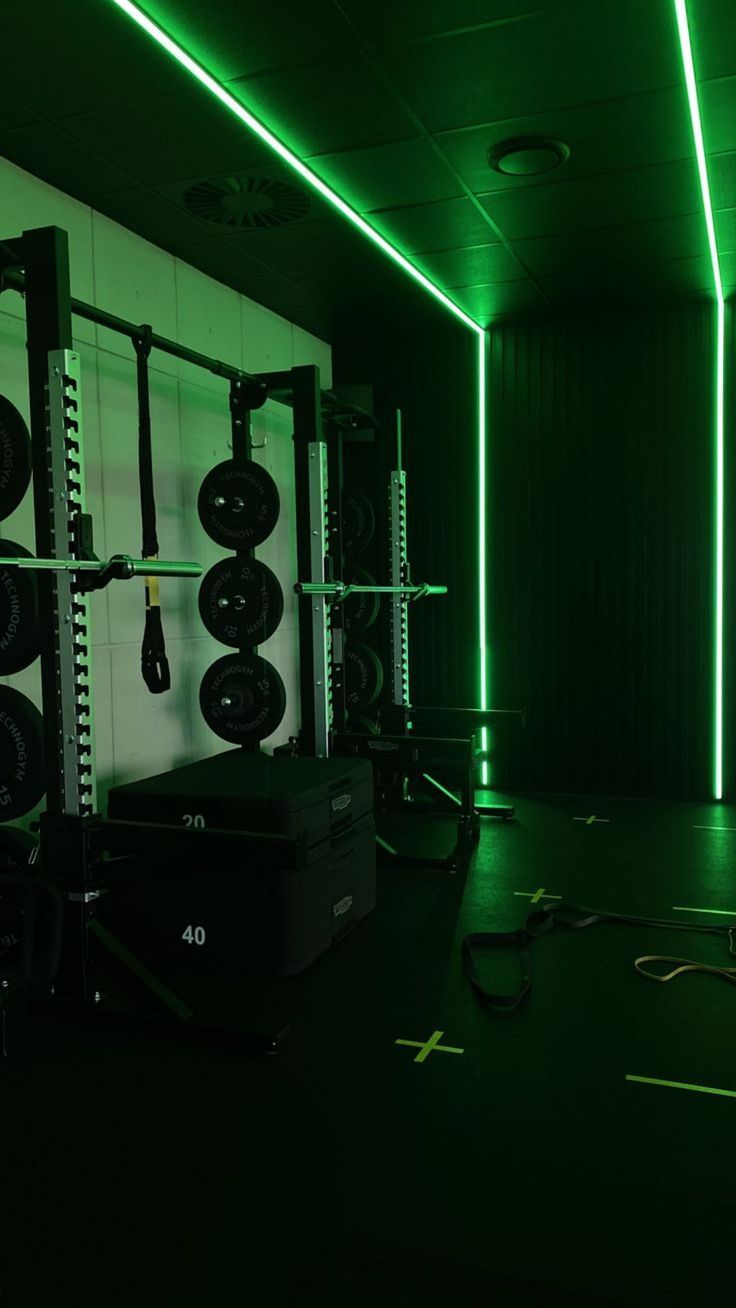 an empty gym room with green lighting and tire racks on the wall, all lit up by neon lights