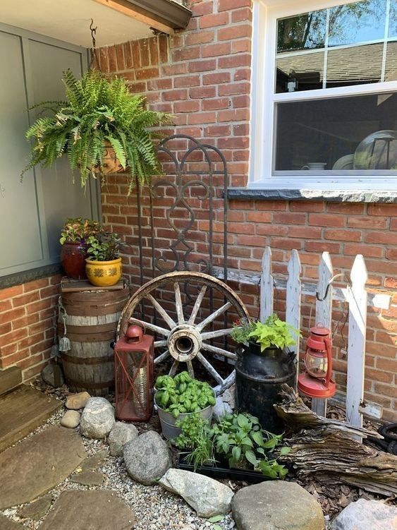 an old wagon is sitting in front of a brick building with potted plants on it